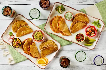 Platters of crispy tacos with salsas and guacamole